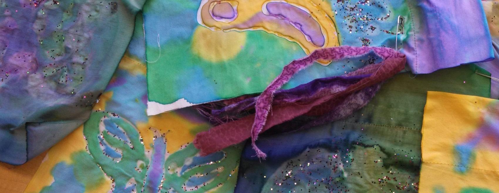 Close-up of multiple Easter flags made of fabric, dyed in blue, green, yellow, and purple, and decorated with butterflies and glitter