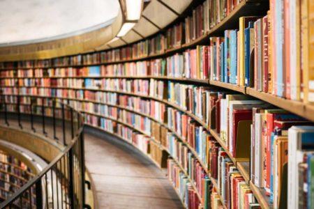 Floor to ceiling curved book shelf with books of many colors