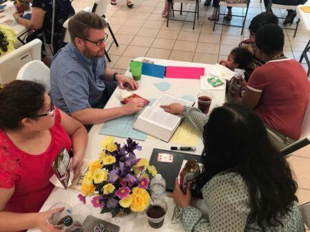 People of different ages and races doing activity at a table.