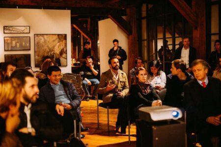 Group of people in dim lit room watching presentation.