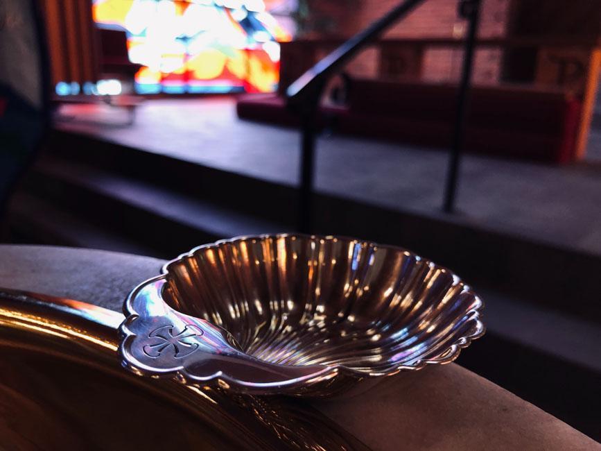 A silver shell on the edge of a baptismal font