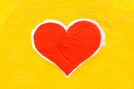 Red heart with white outline on yellow background.