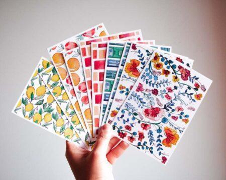 Hand holding postcards with different designs.
