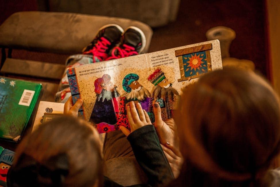 Two children reading a book with an image of three kings.