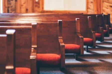 Church pews with red cushions.