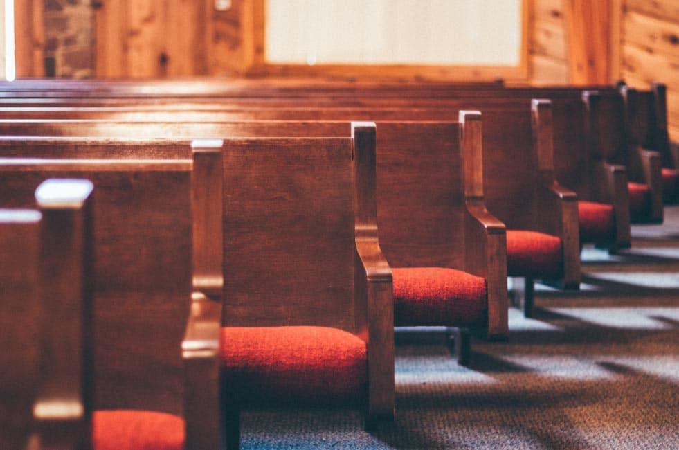 Church pews with red cushions.