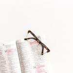 Black framed eyeglasses on top of open Bible.