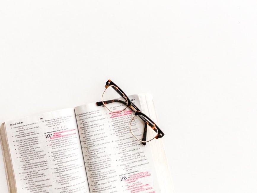 Black framed eyeglasses on top of open Bible.