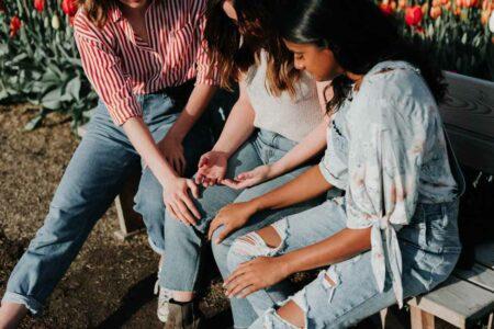 Three young people on a bench in prayer.