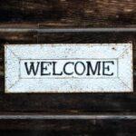 A white sign that reads "Welcome" with dark wood in the background.