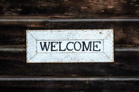 A white sign that reads "Welcome" with dark wood in the background.