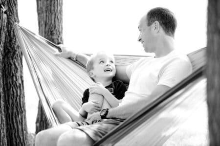 Black and white image of father and son in hammock.