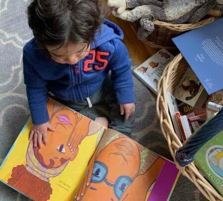 Child with dark brown hair looks at picture book.