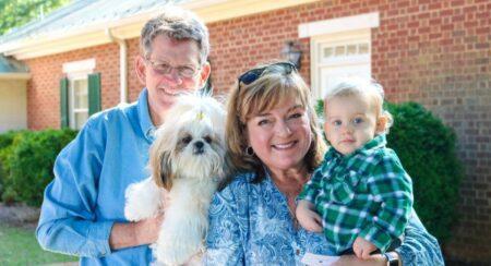 two adults holding small dog and young child