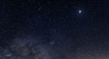 A star-filled sky with the glow from the sun on the horizon
