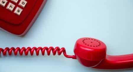 Close-up of portions of red corded phone on light blue background