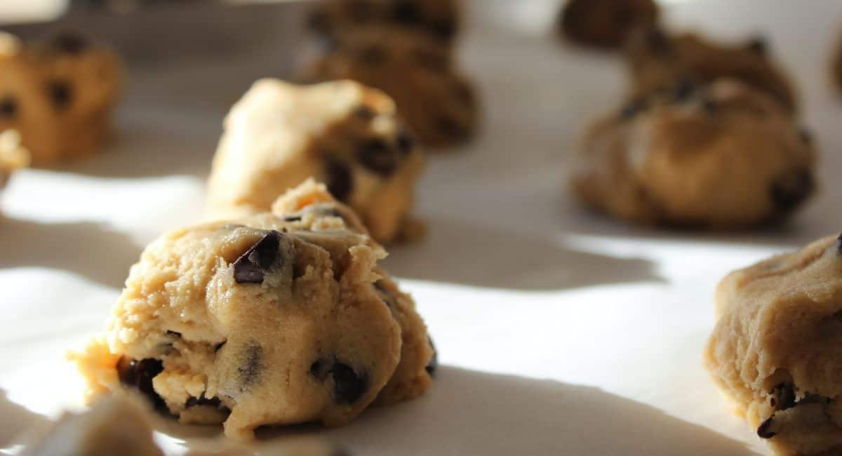 Mounds of cookie dough spaced apart on white surface