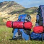Two backpacks on grass with hills in background