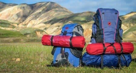 Two backpacks on grass with hills in background