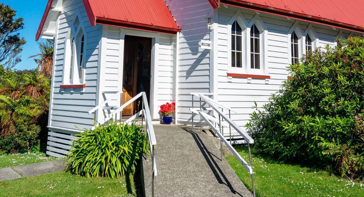 Gray ramp up to the entrance of a white building with a red roof