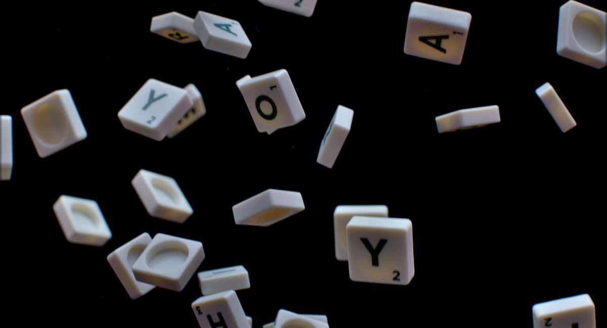 Tiles with alphabet letters in midair in front of a black background