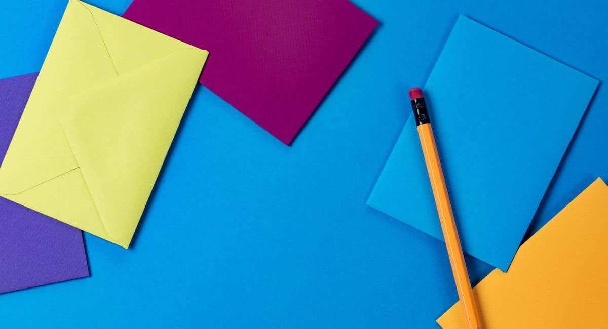 Envelopes in different colors with a pencil on a blue background