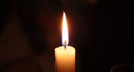 Close-up of a lit ivory-colored candle with a black background