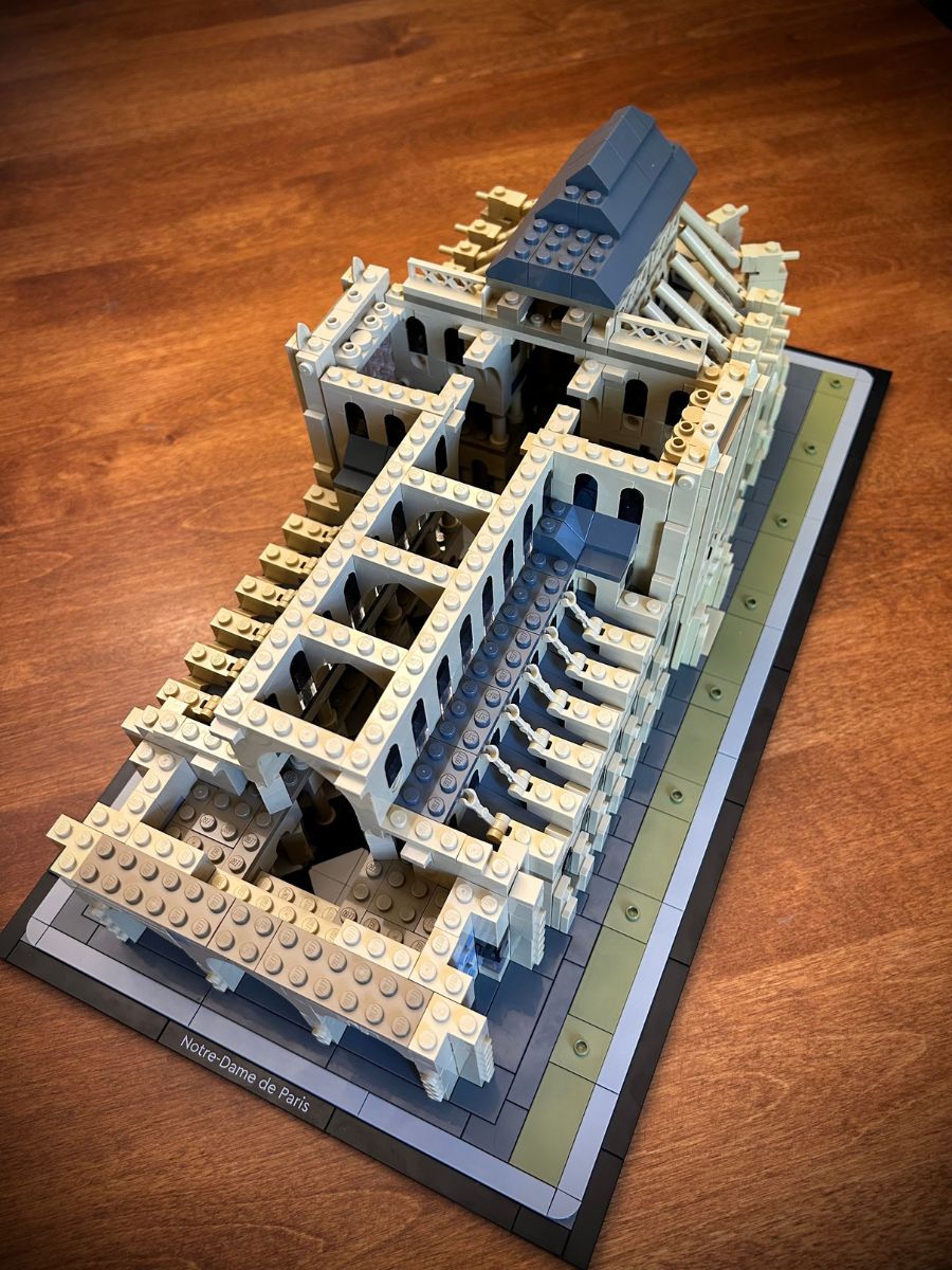 Angled aerial view of the cross shape of Lego Notre Dame Cathedral on a tan wood surface
