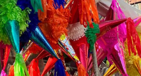 Close-up of star-shaped piñatas in various colors: green, blue, orange, pink, red, and yellow