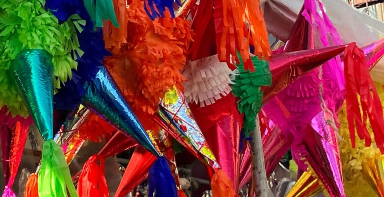 Close-up of star-shaped piñatas in various colors: green, blue, orange, pink, red, and yellow