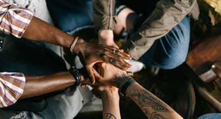 Close-up of multiple human hands with dark, medium light, and light skin tones stacked together