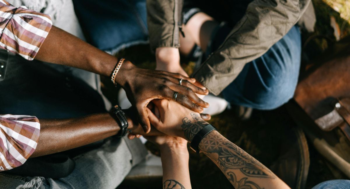 Close-up of multiple human hands with dark, medium light, and light skin tones stacked together