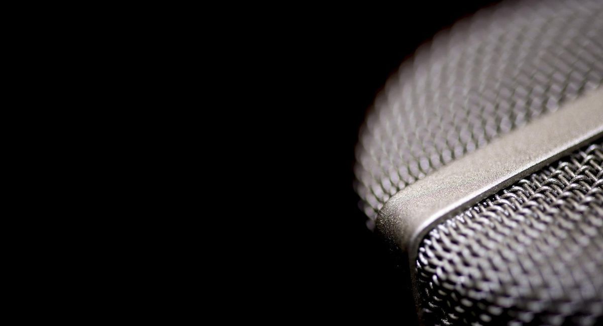 Close-up of silver microphone on the right against a black background