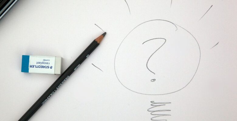 Gray pencil drawing of question mark in a circle surrounded by short rays along the top and a spiral squiggle at the bottom with a white eraser and gray pencil to the left on an off-white background