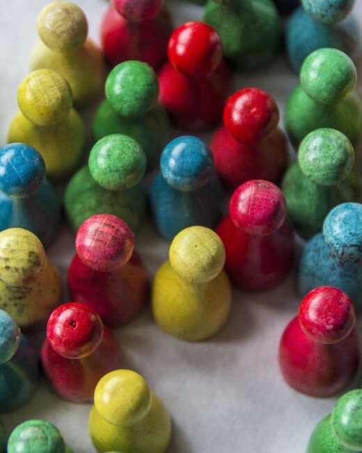 Aerial view of a bunch of board game figures in green, blue, yellow, and red on a gray surface