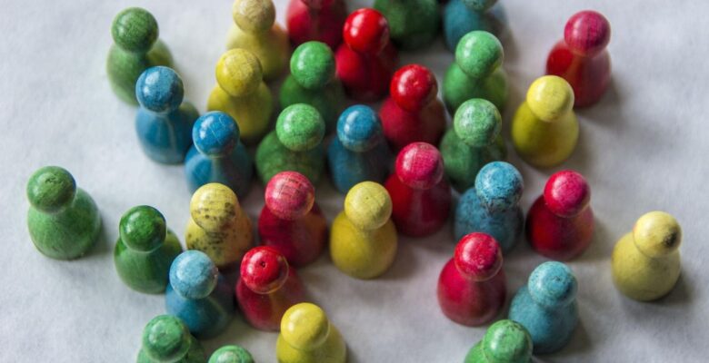 Aerial view of a bunch of board game figures in green, blue, yellow, and red on a gray surface