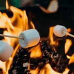 Three marshmallows on wooden sticks roasting over a fire