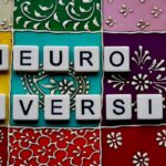 White tiles with black letters that say "NEURODIVERSITY" on a background of multi-colored blocks with various designs in black and white