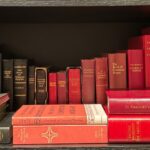 A collection of various editions of the Book of Common Prayer, derivatives, and associated liturgical texts on a dark brown bookshelf