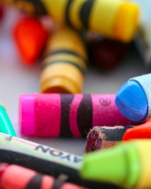 Close-up of many crayons in different colors in disarray on a gray surface